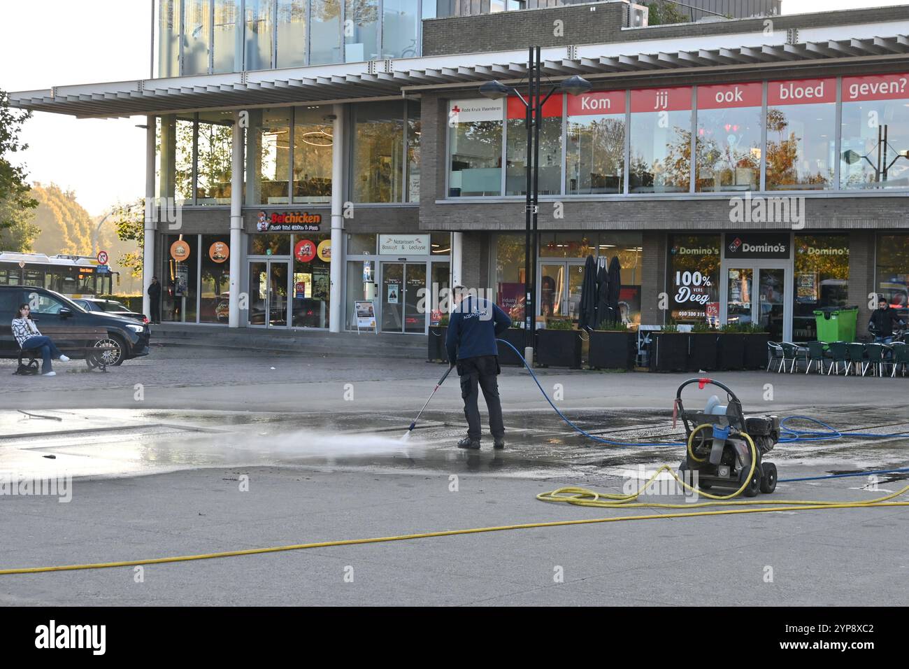 Worker cleaning fountain with a pressure washer outside Brugge railway station – Bruges, Belgium – 24 October 2024 Stock Photo