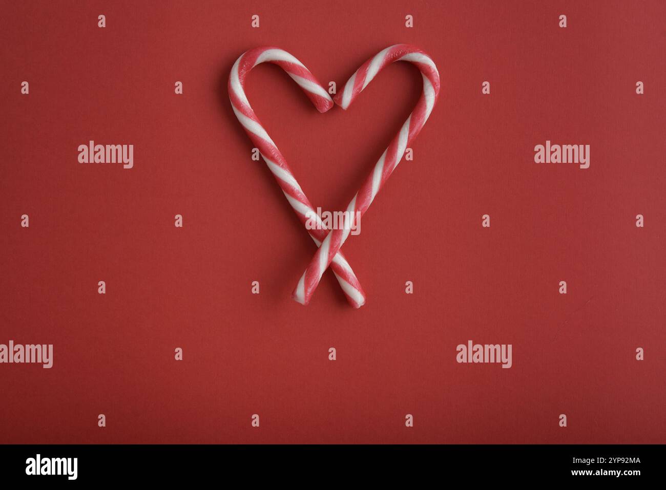 Christmas candy canes heart-shaped  on red background, top view Stock Photo