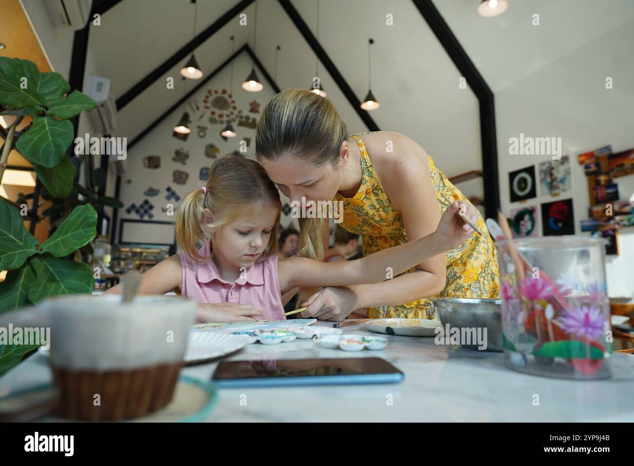 A young mother and her daughter enjoy a creative art session at home ...