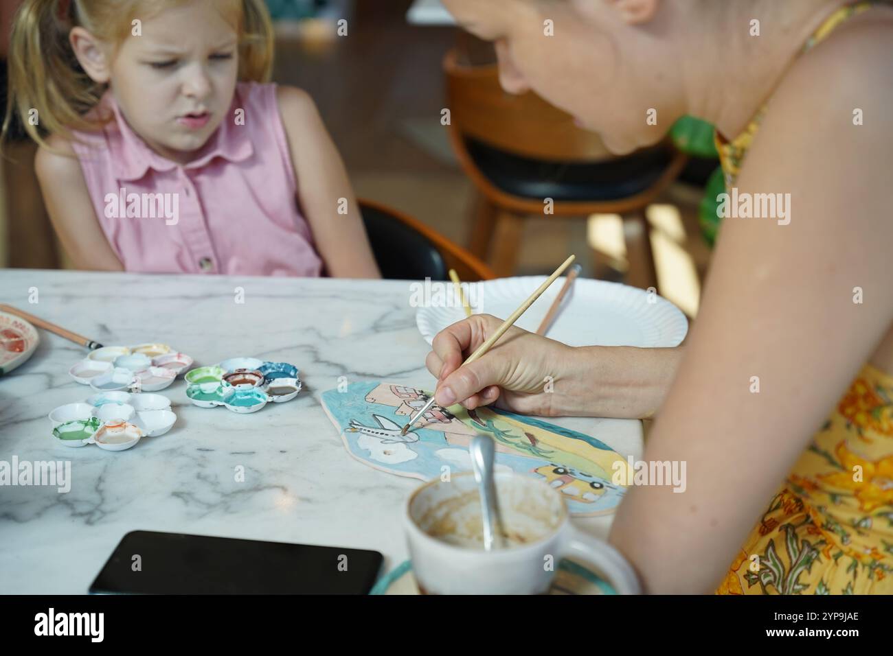 A young mother and her daughter enjoy a creative art session at home ...