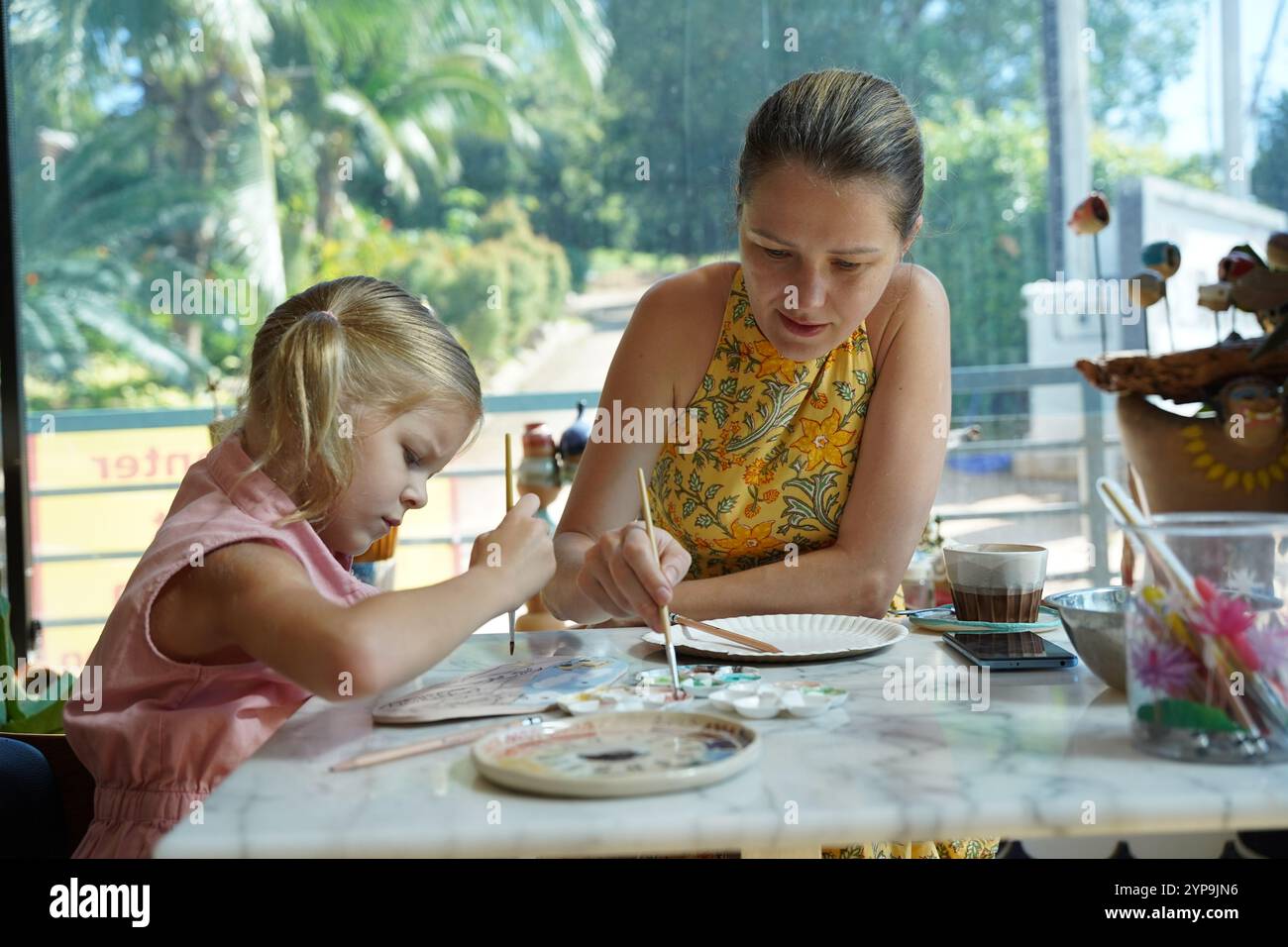 A young mother and her daughter enjoy a creative art session at home ...