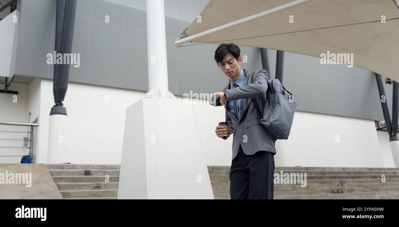Asian man multitasking with phone and coffee outdoors Stock Photo - Alamy