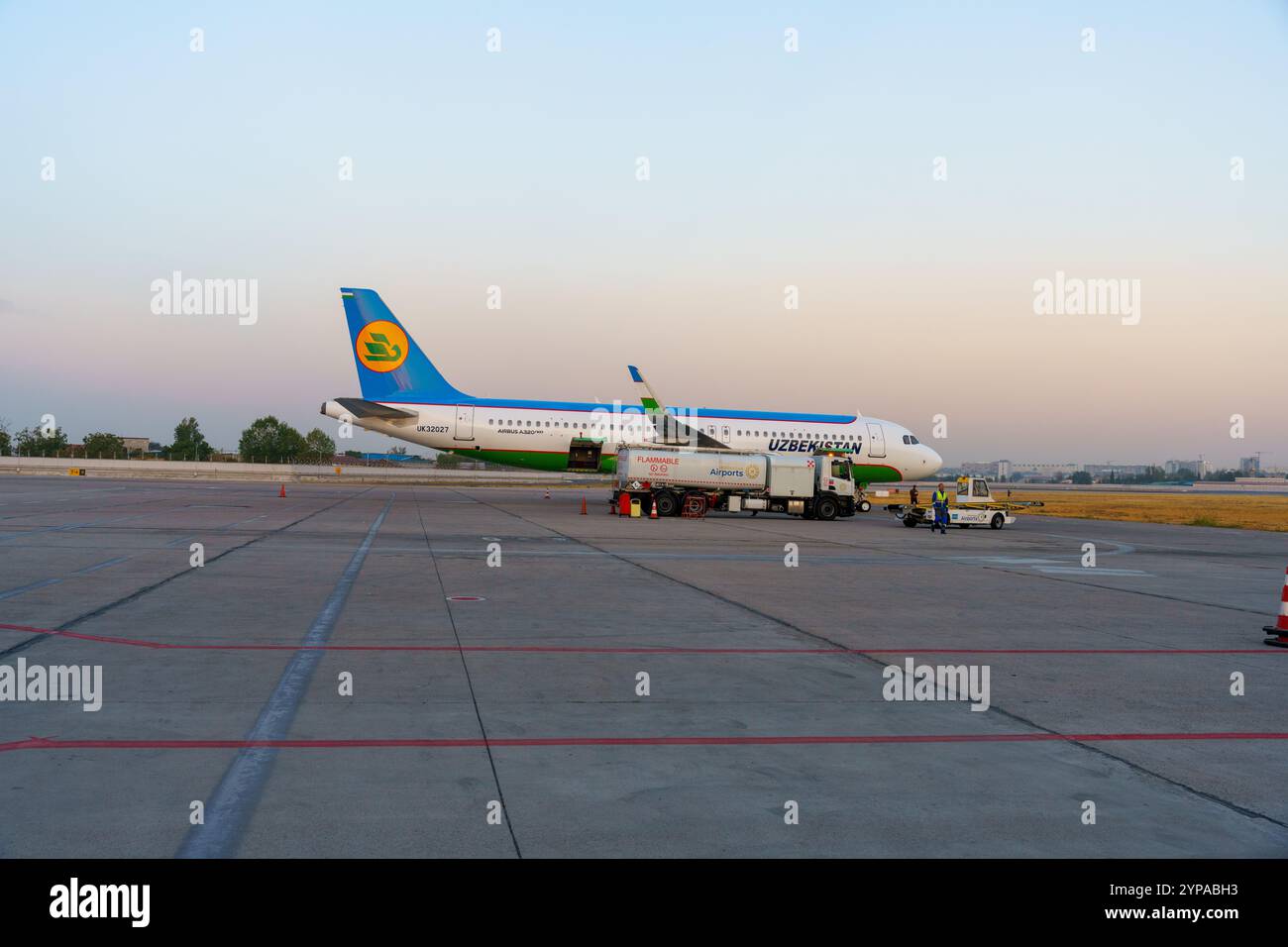 A large airplane is parked on the tarmac with a truck in front of it Stock Photo