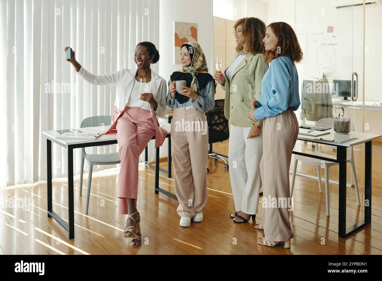Four Colleagues Taking a Group Selfie in Office Setting Stock Photo