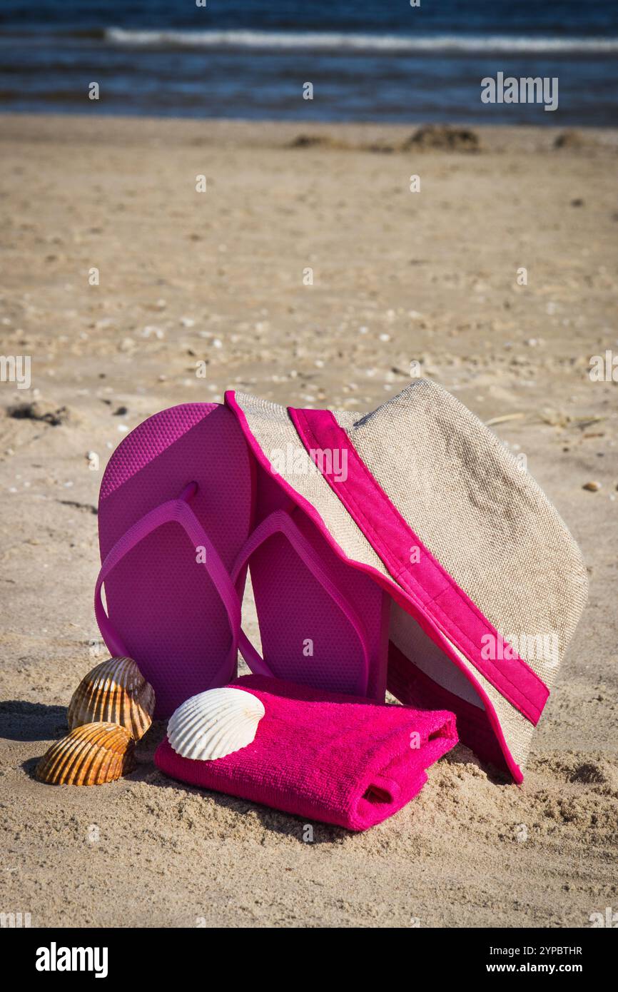 Pink flip flop, straw hat and fluffy towel on beach. Accessories for ...