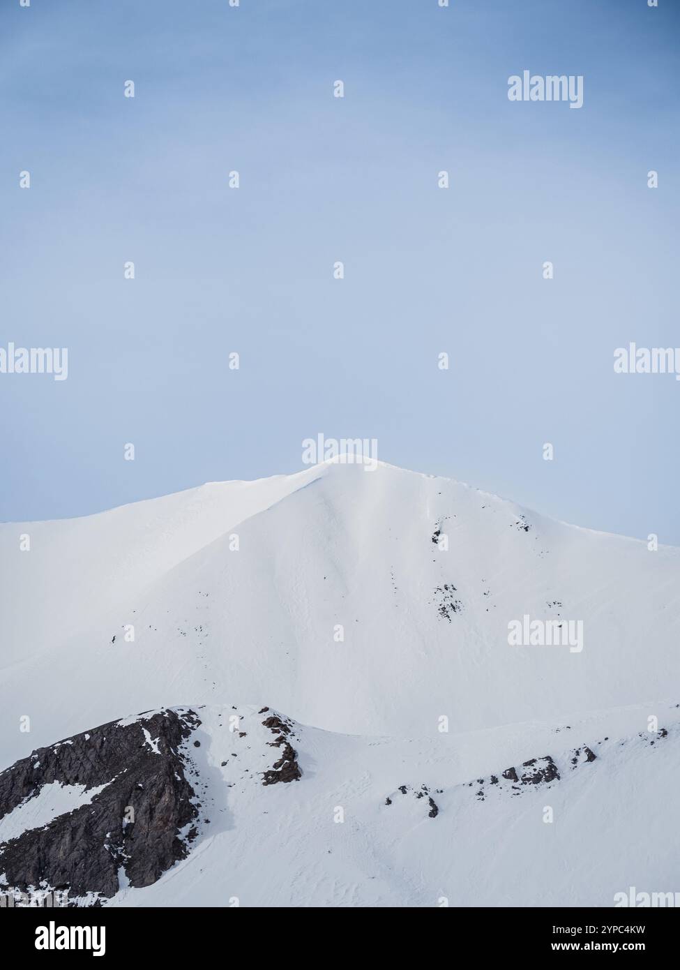 A pristine snowy mountain peak rises against a clear blue sky. The ...