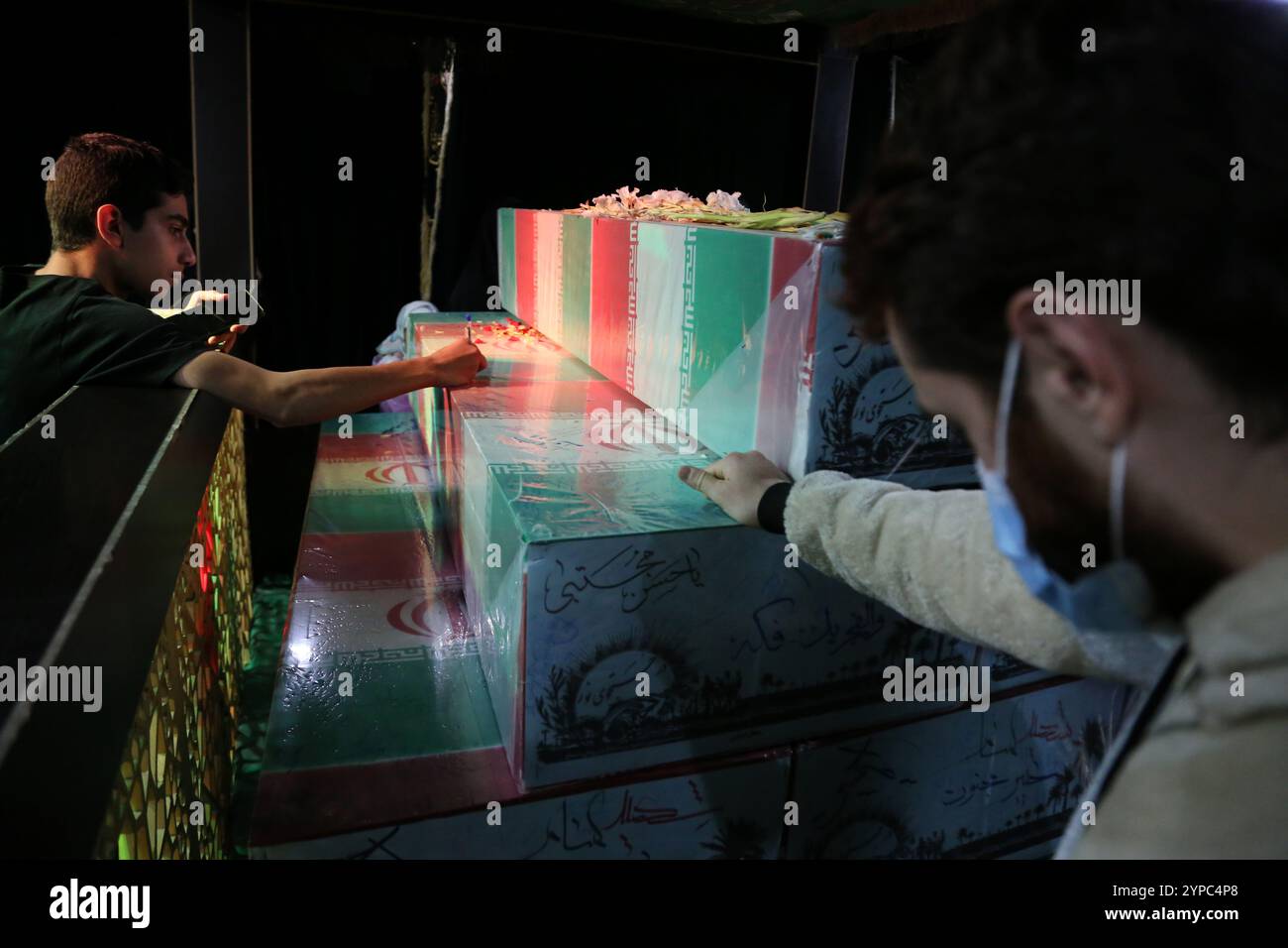 Tehran, Iran. 29th Nov, 2024. Iranian men touch the coffins of anonymous martyrs during the funeral ceremony of Brigadier General Kiyomarth Porhashmi, a senior officer of the Islamic Revolutionary Guard Corps (IRGC) Quds Force, who was killed in Aleppo, Syria. The IRGC Quds Force is a unit of Iran's Revolutionary Guard that conducts military, intelligence, and support operations abroad to advance Iran's regional influence. (Credit Image: © Rouzbeh Fouladi/ZUMA Press Wire) EDITORIAL USAGE ONLY! Not for Commercial USAGE! Stock Photo