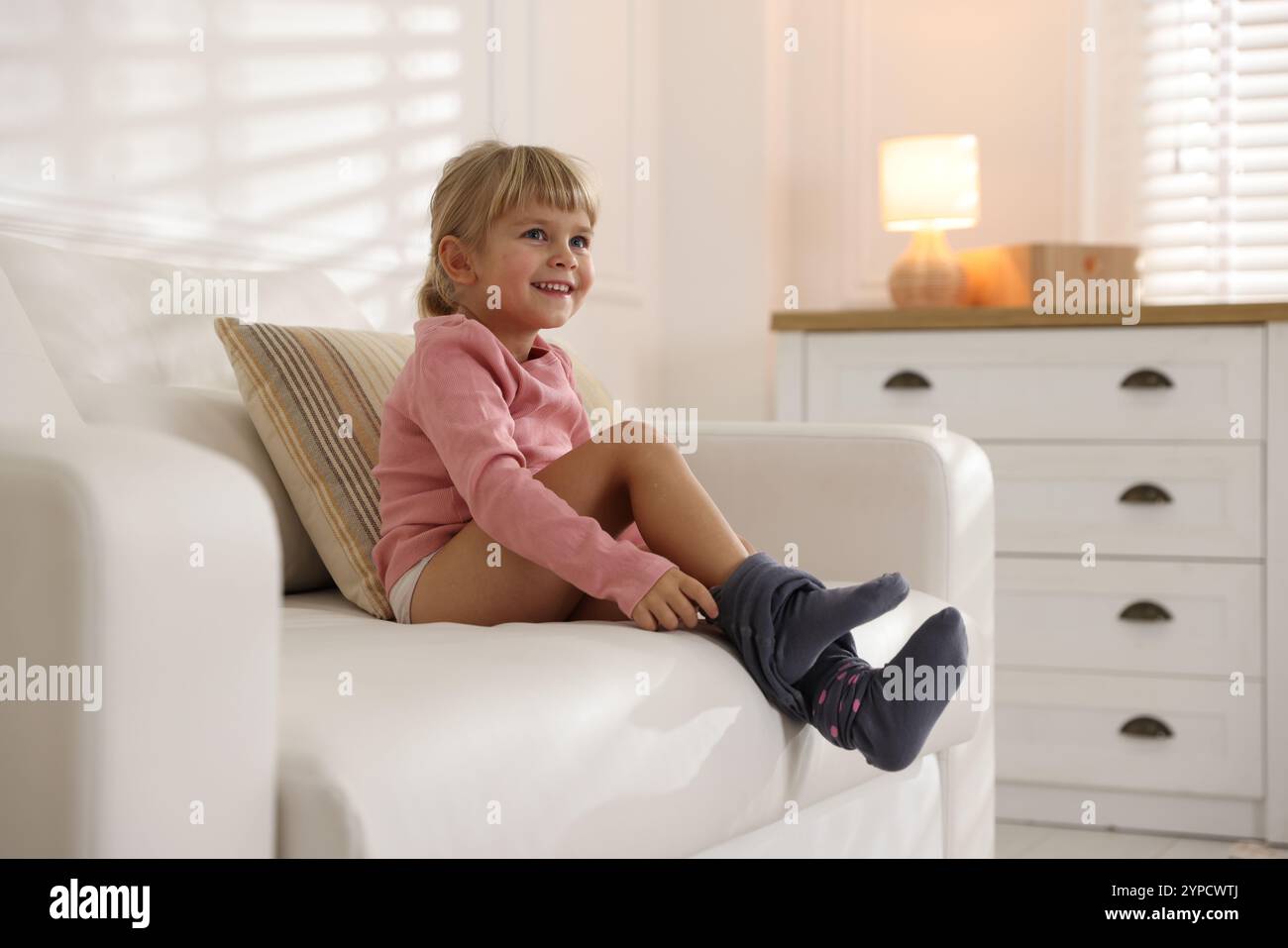 Little girl putting on soft tights at home. Space for text Stock Photo