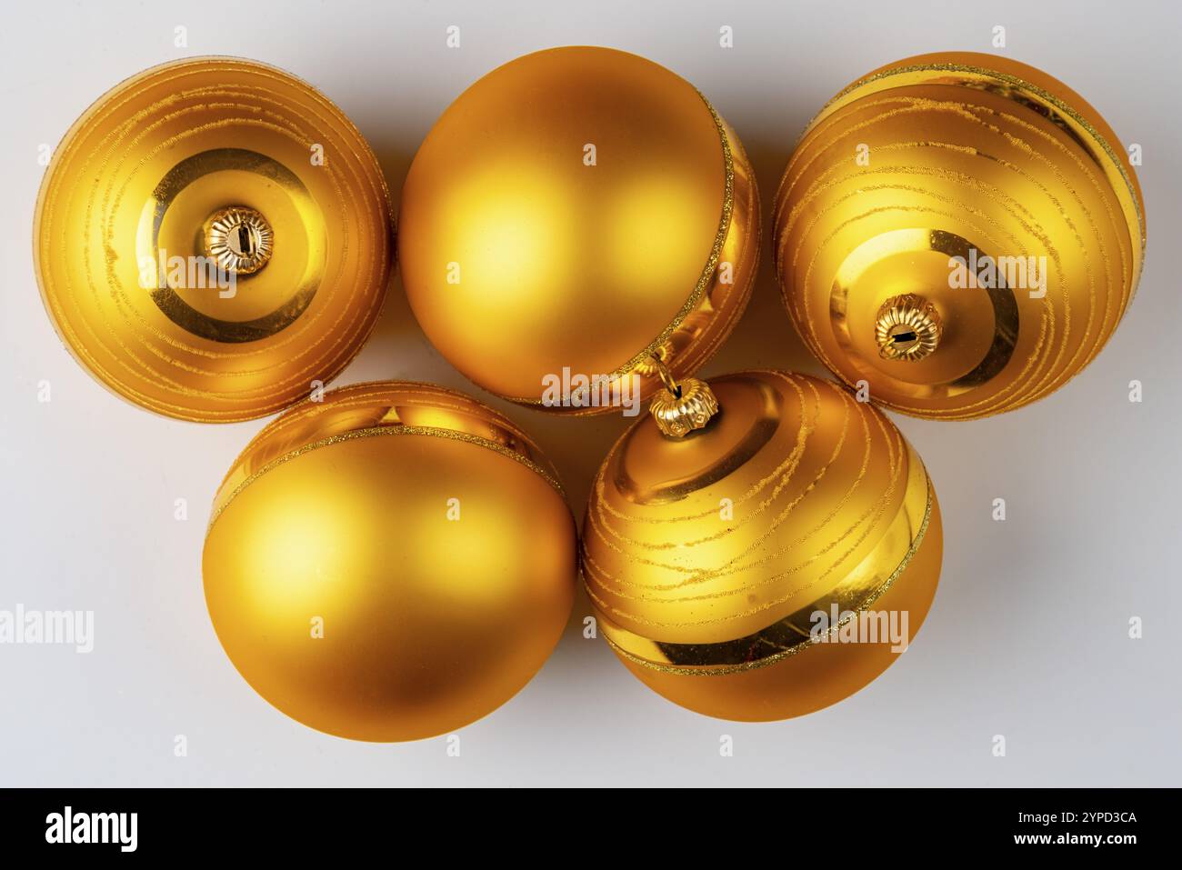 Five golden Christmas baubles lie on a white surface Stock Photo