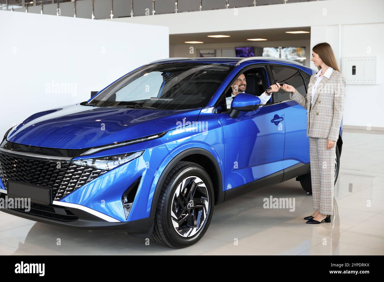 Saleswoman giving key to client inside new car in salon Stock Photo - Alamy