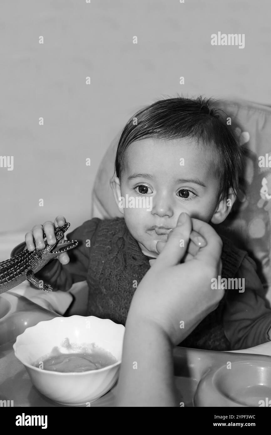 The baby enjoys eating when his mother feeds him carefully and lovingly. Monochrome photography Stock Photo