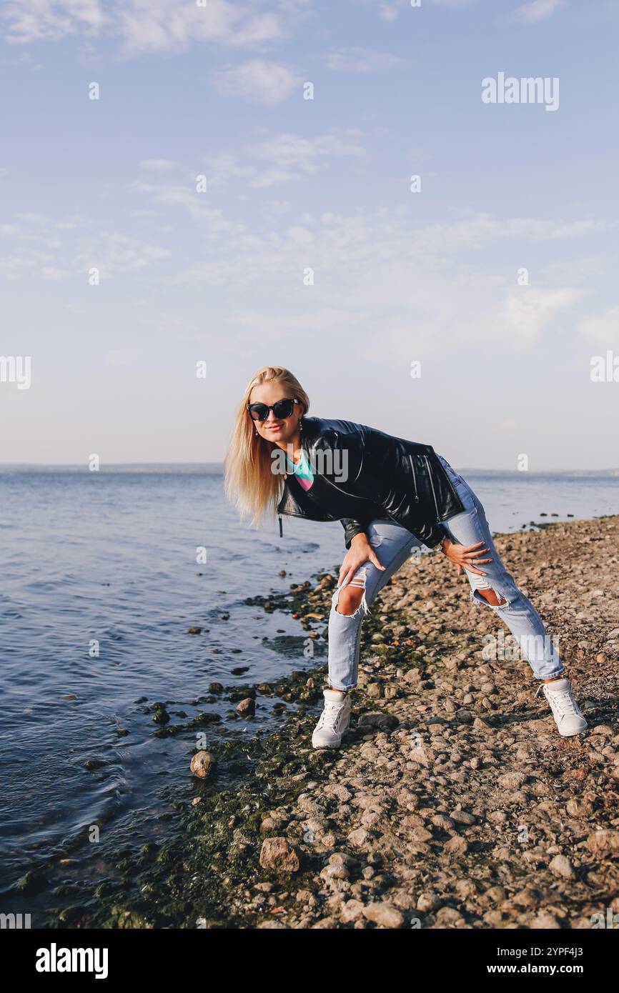 Beach Ripped Fashion model posing on a rocky beach, wearing sunglasses, a leather ...