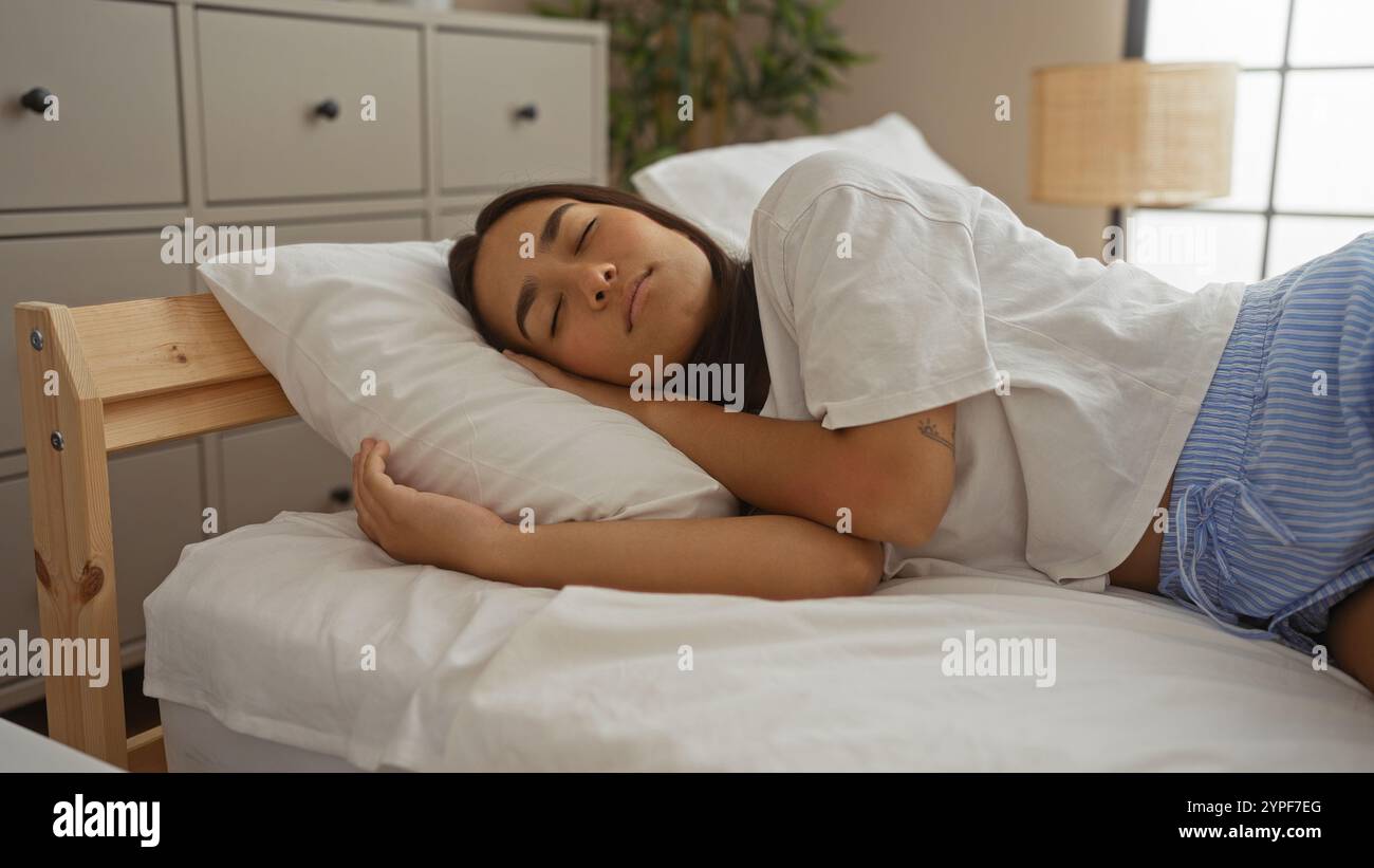 Young woman sleeping peacefully on a bed in a cozy bedroom within a serene home interior, showcasing a relaxed indoor atmosphere with calm and tranqui Stock Photo