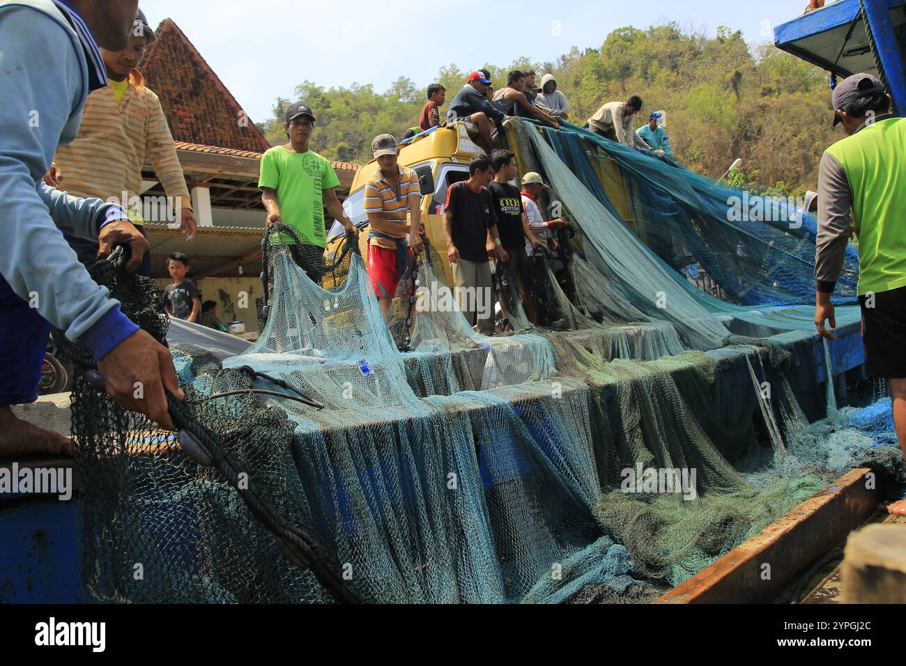 Fishermen work together to tidy up large fishing gear nets. Stock Photo