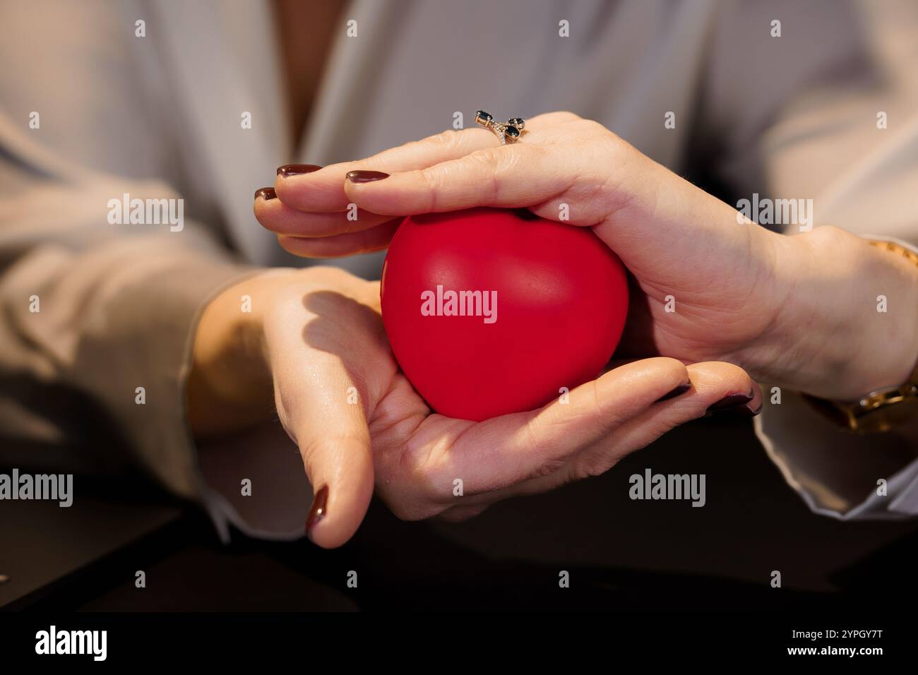 Hands Holding a Red Heart Stress Ball in a Close-Up Setting. Stock Photo