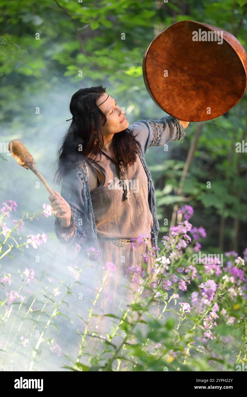 Shamnan Ritual Shaman woman performs a ritual with a tambourine in the forest in the ...
