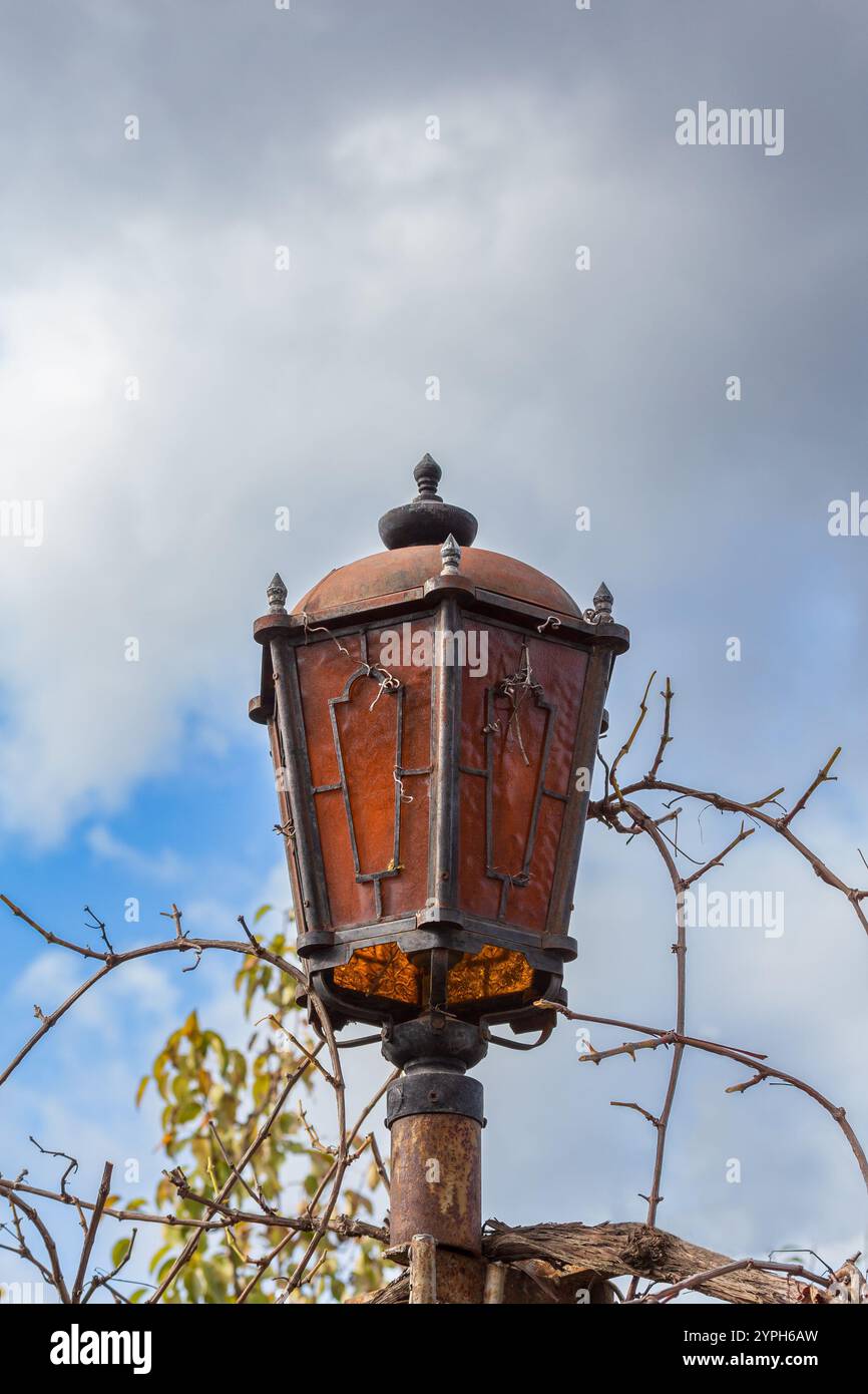 Old rusty lantern between branches against the sky, daytime Stock Photo