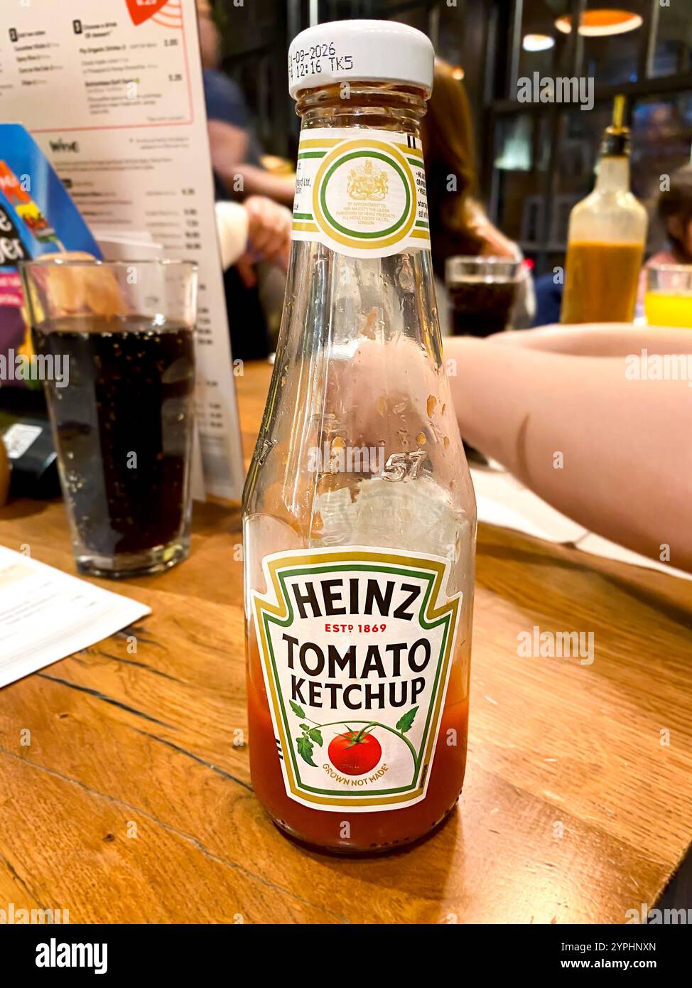 A bottle of Heinz Tomato Ketchup on a table in a restaurant is nearly empty. - Smartphone Captured Stock Image
