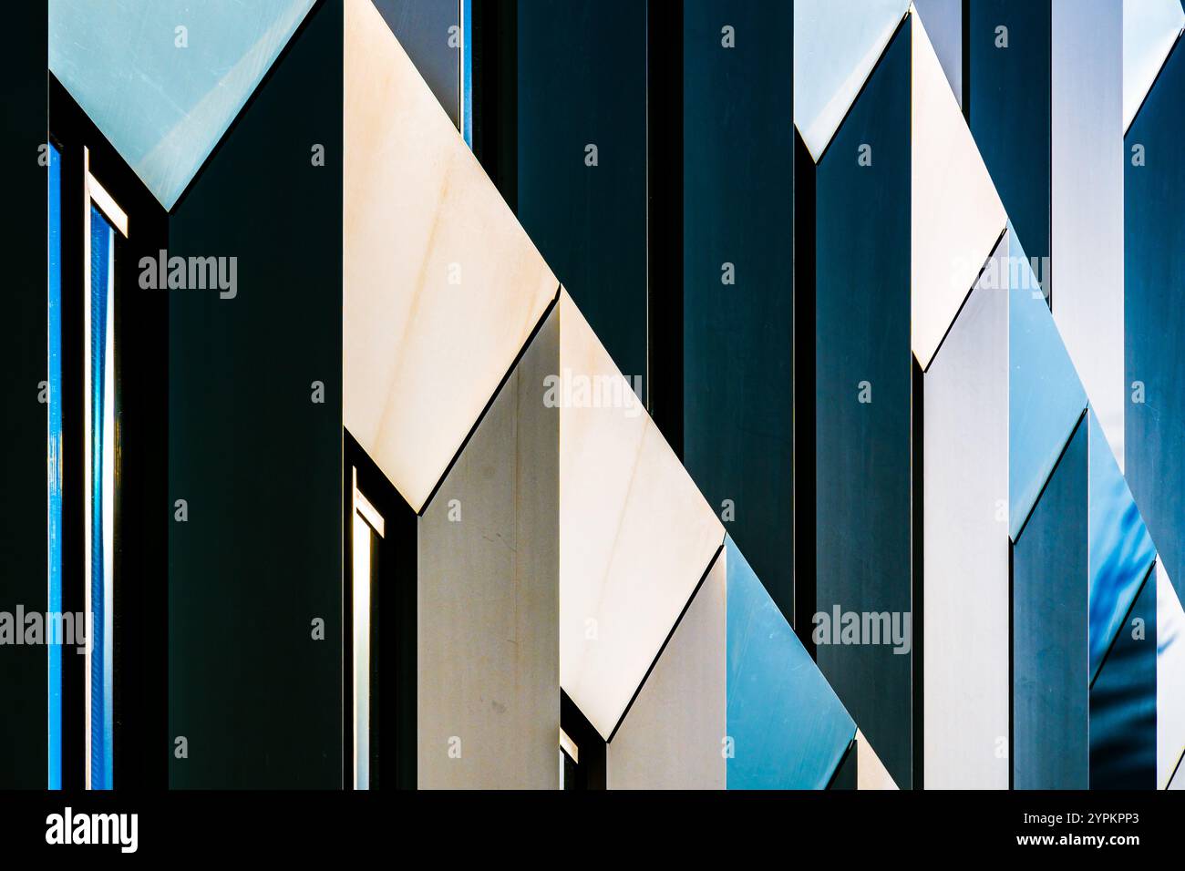 Abstract Close-Up of Modern Building Facade with Angular Patterns and Reflective Blue Windows Stock Photo