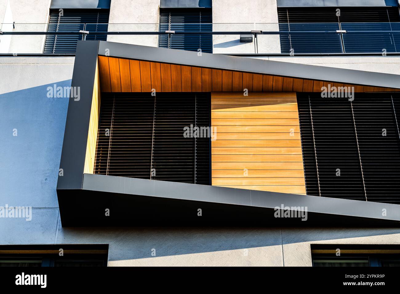 Modern Architectural Facade with Geometric Protrusions and Reflective Windows in Sunlight Stock Photo