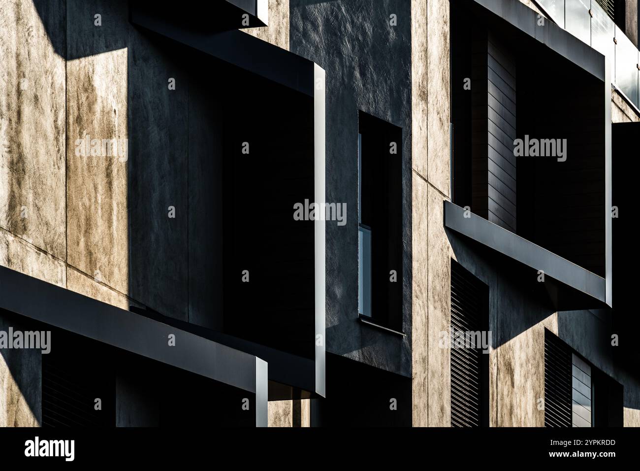 Modern Architectural Facade with Geometric Protrusions and Reflective Windows in Sunlight Stock Photo