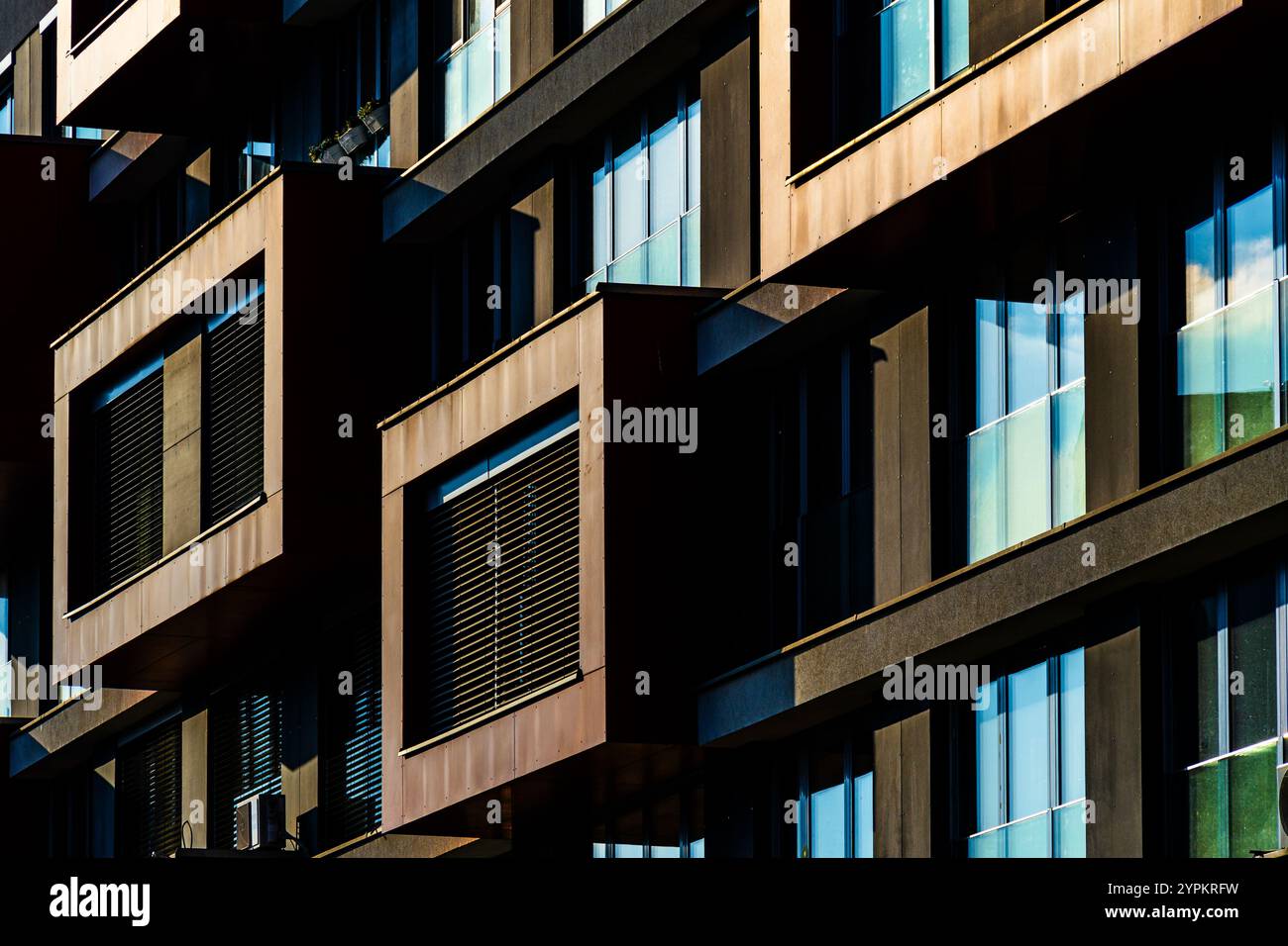 Modern Architectural Facade with Geometric Protrusions and Reflective Windows in Sunlight Stock Photo