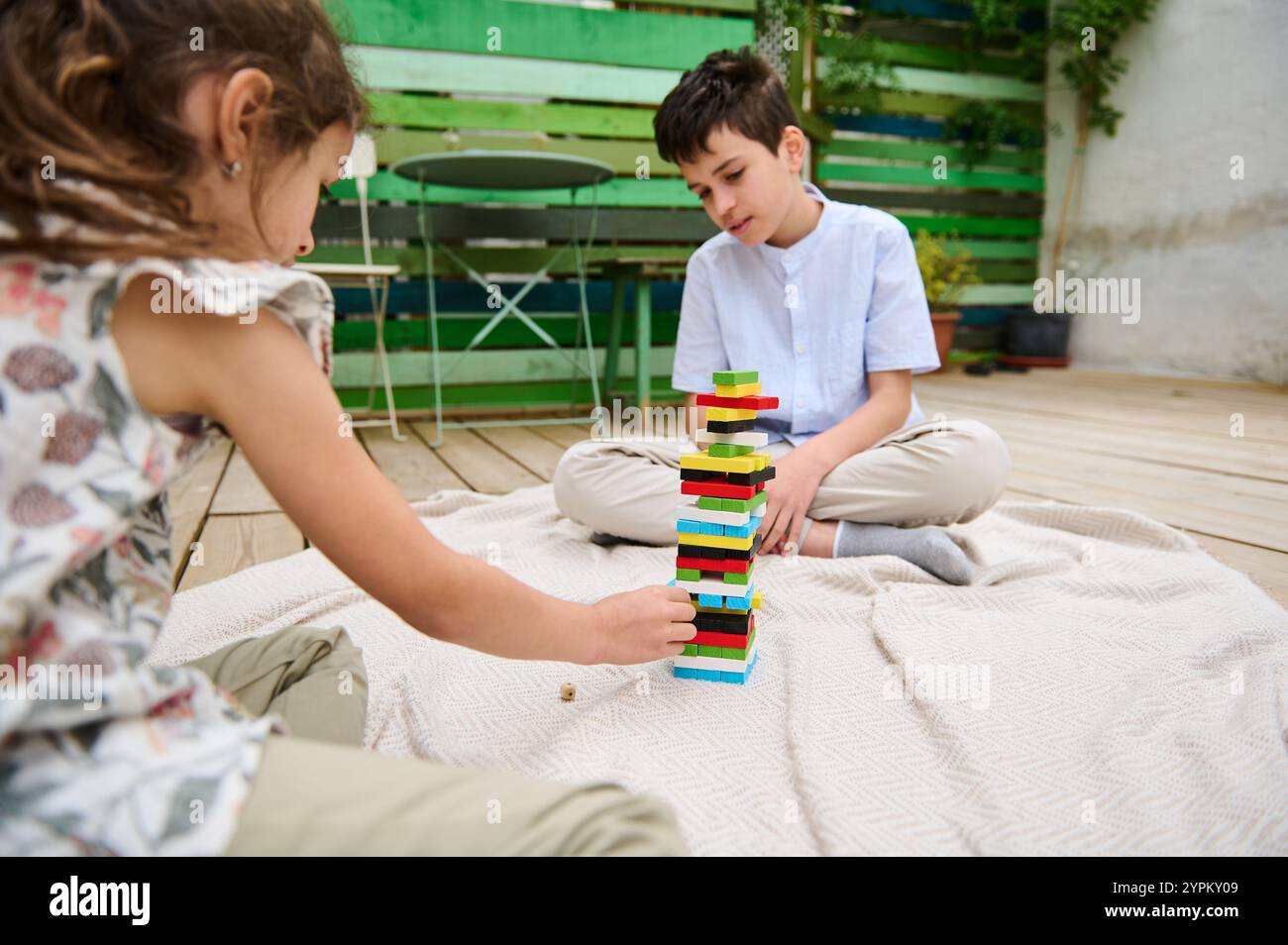 Two children enjoy building a tower with colorful blocks while sitting ...