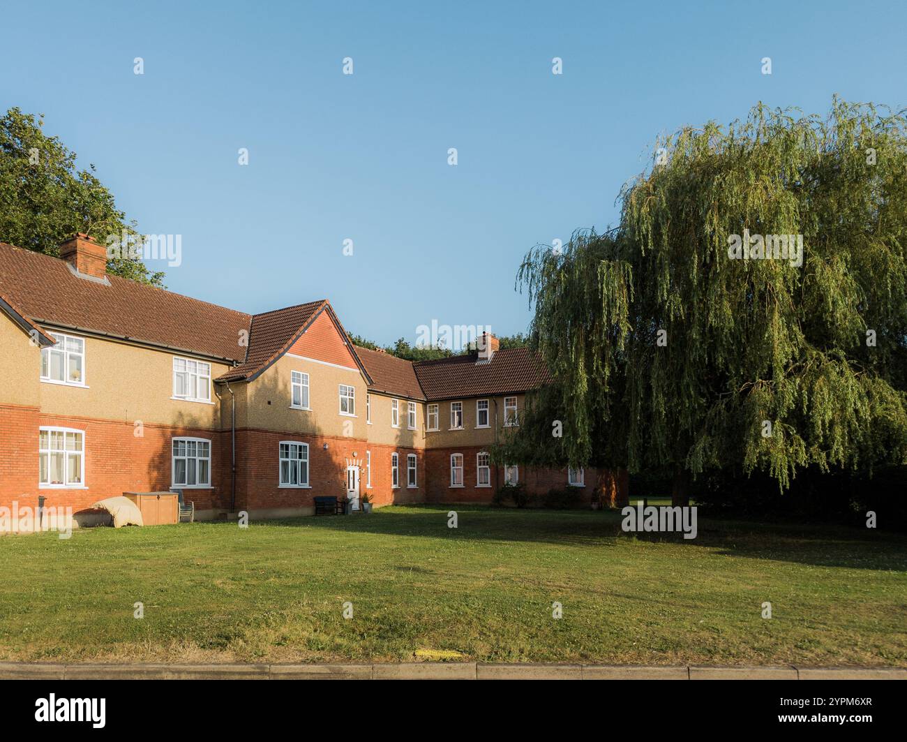 View of Traditional suburban housing with a red-brick facade, lush green lawn ...