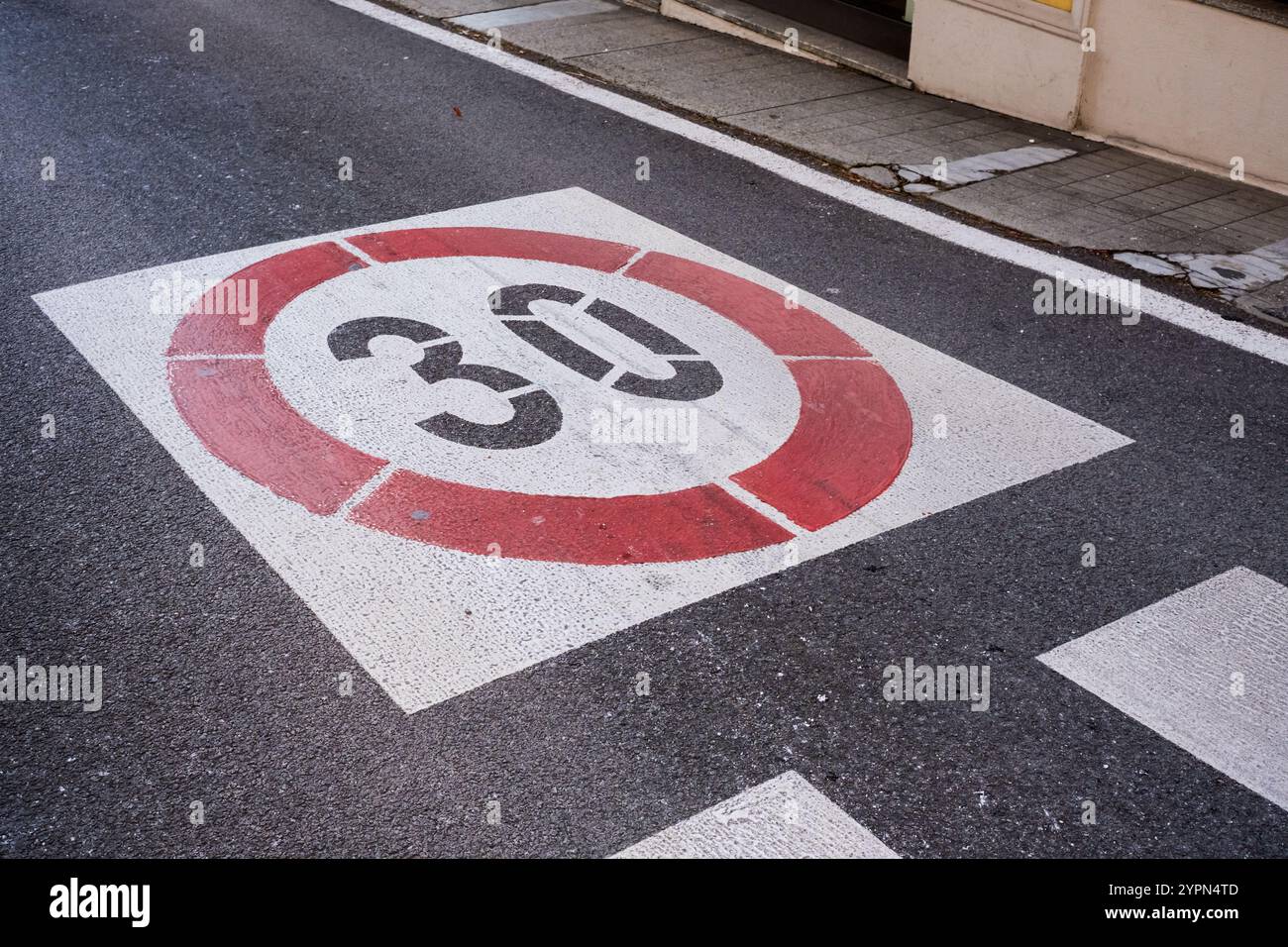 A speed limit sign painted on the asphalt of an urban road indicating the number thirty Stock Photo