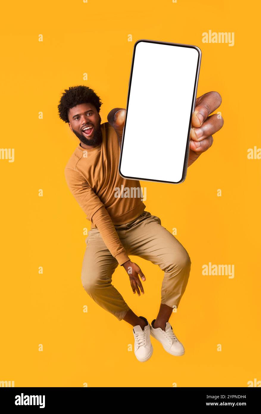 Excited black guy holding smartphone, jumping up Stock Photo - Alamy