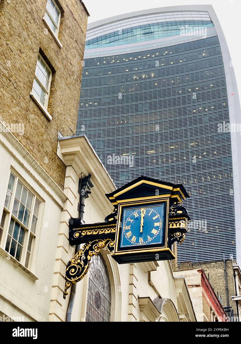 Turret clock of St Mary-at-Hill church stuck at twelve o'clock with the facade of The Fenchurch Building in the background, London, England - Smartphone Captured Stock Image