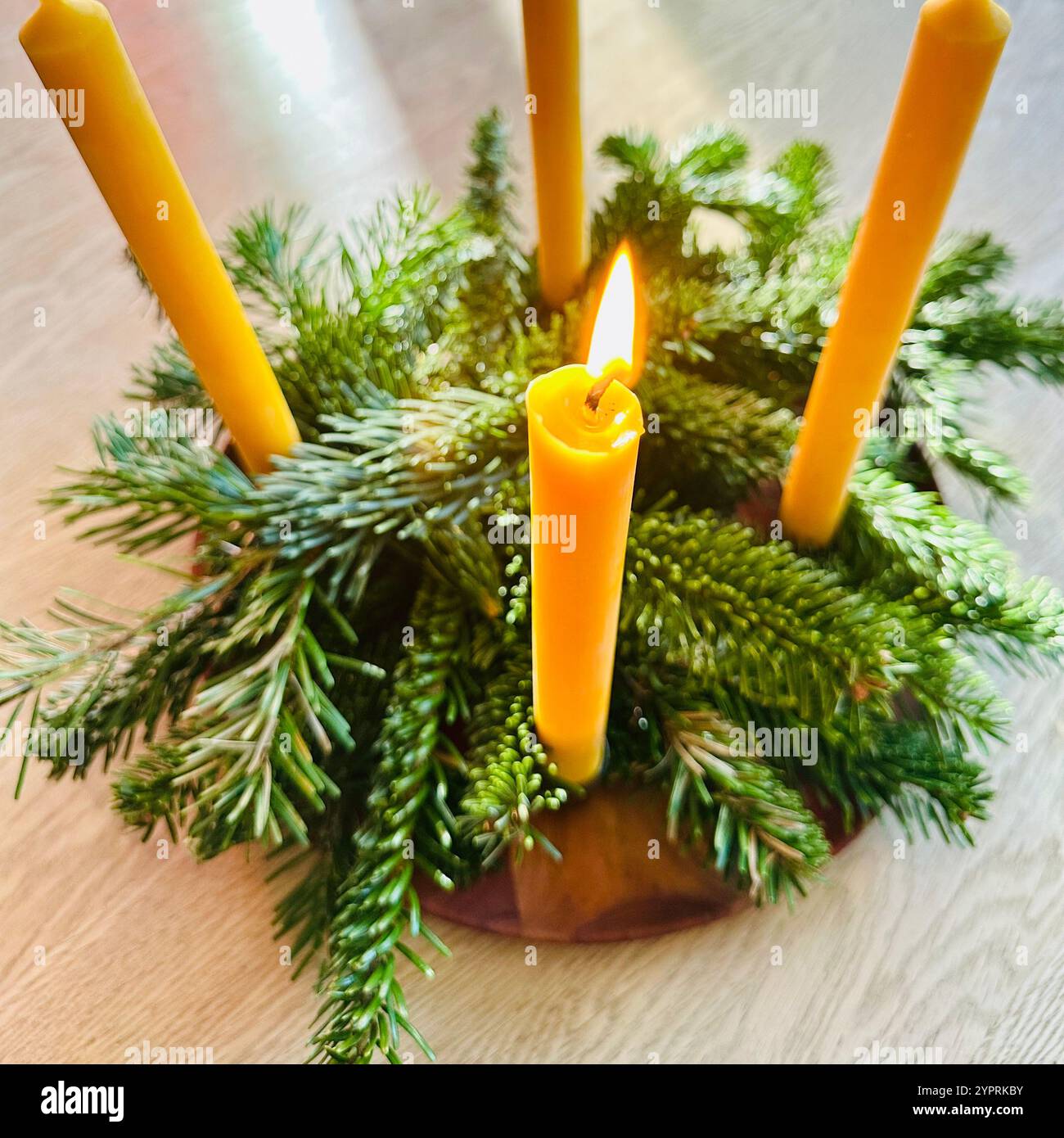 An advent wreath made with fir sprigs and with four yellow beeswax candles, one of them is lit - Smartphone Captured Stock Image
