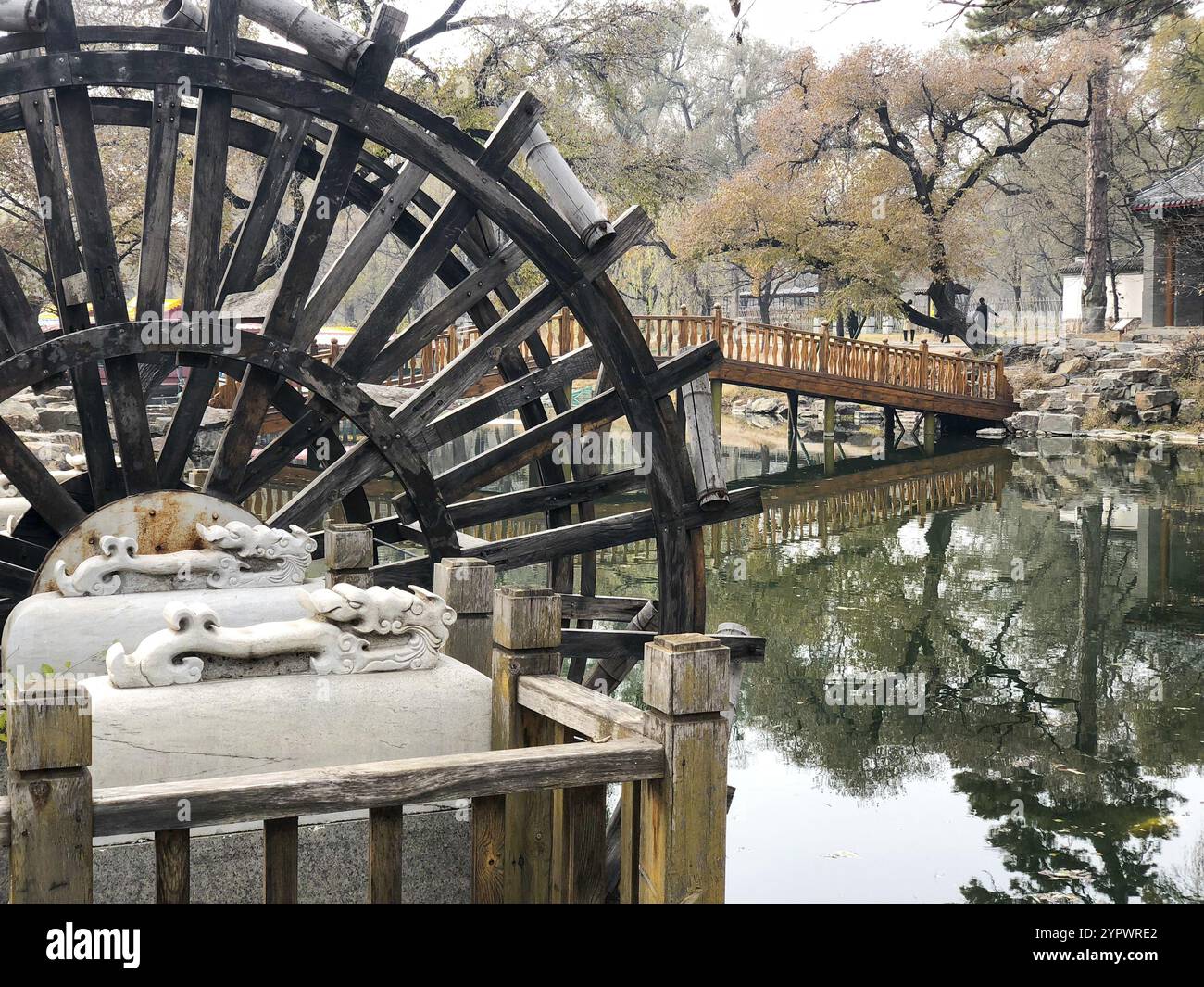 Water mill wheel in a calm little river and little pavilion on the background at The Imperial Summer Palace of The Mountain Resort in Chengde. China Stock Photo