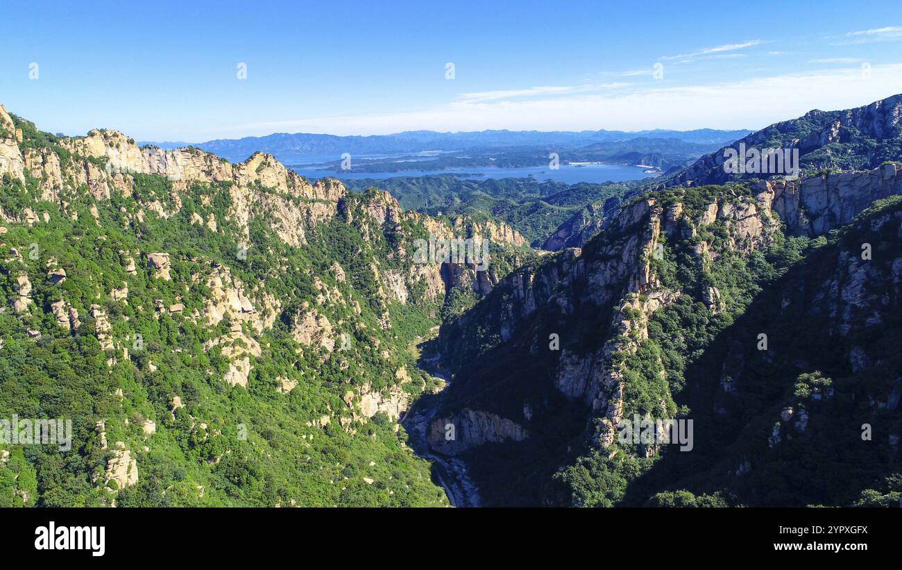 Aerial view of mountain with water reservoir on the background with beautiful blue sky. Landscape of mountain in natural reserve park. Miyun, Beijing Stock Photo