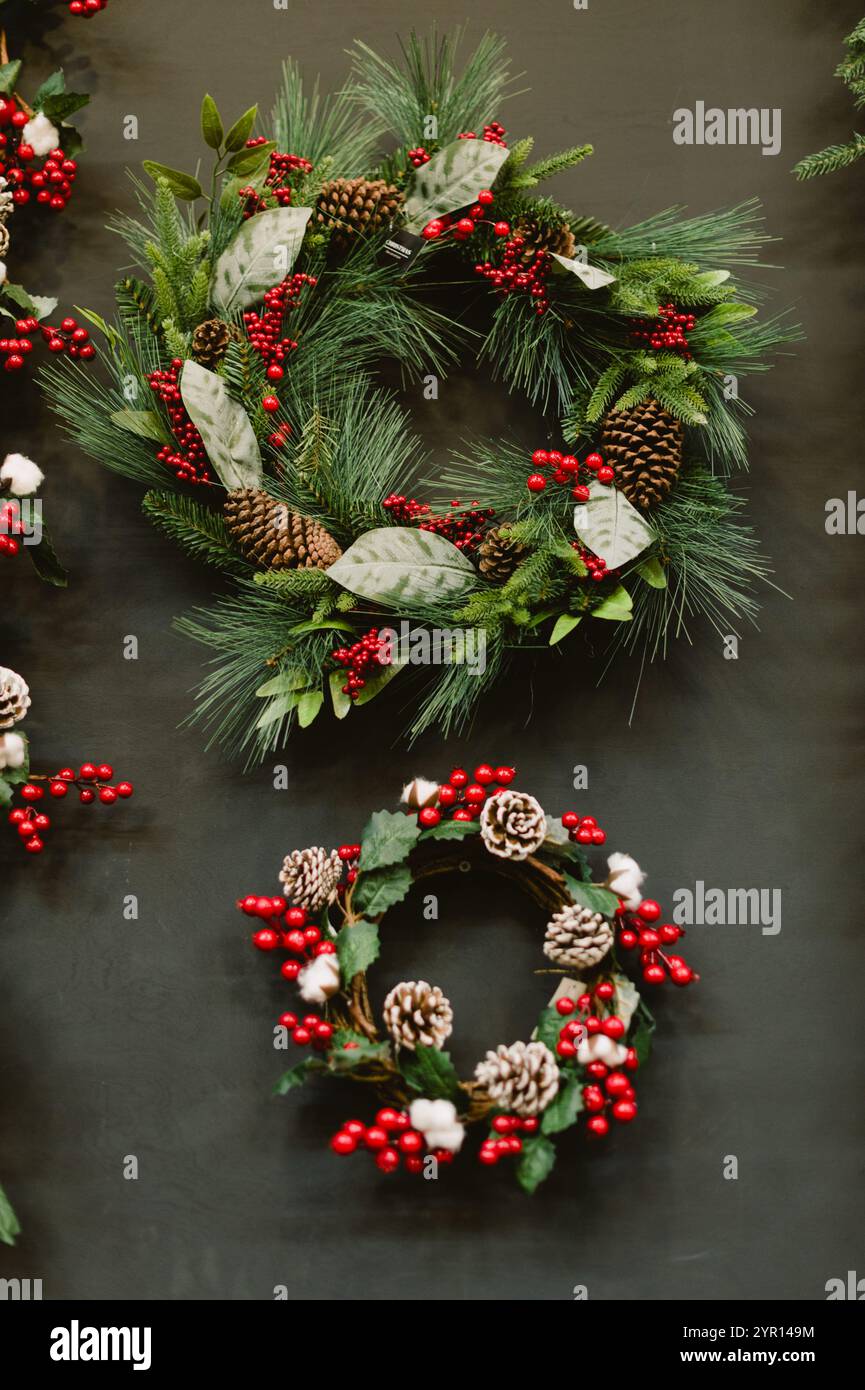 Two wreaths with red berries and pine cones. One is on the left and the ...