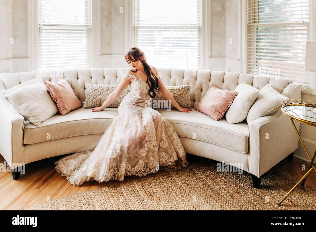 Young bride sitting indoors on white circular couch Stock Photo