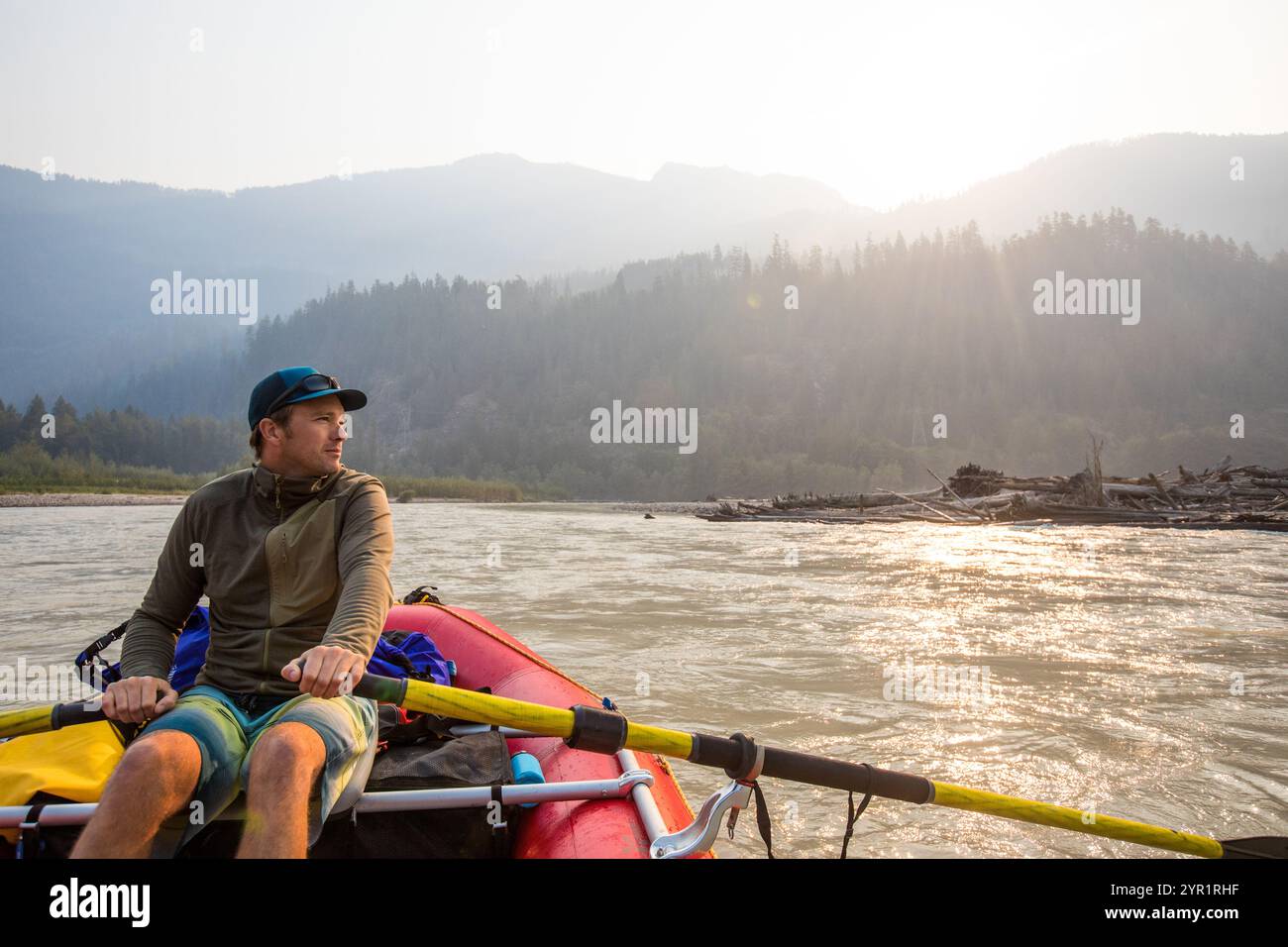 Man looks thoughtful while rowing raft on scenic river Stock Photo - Alamy