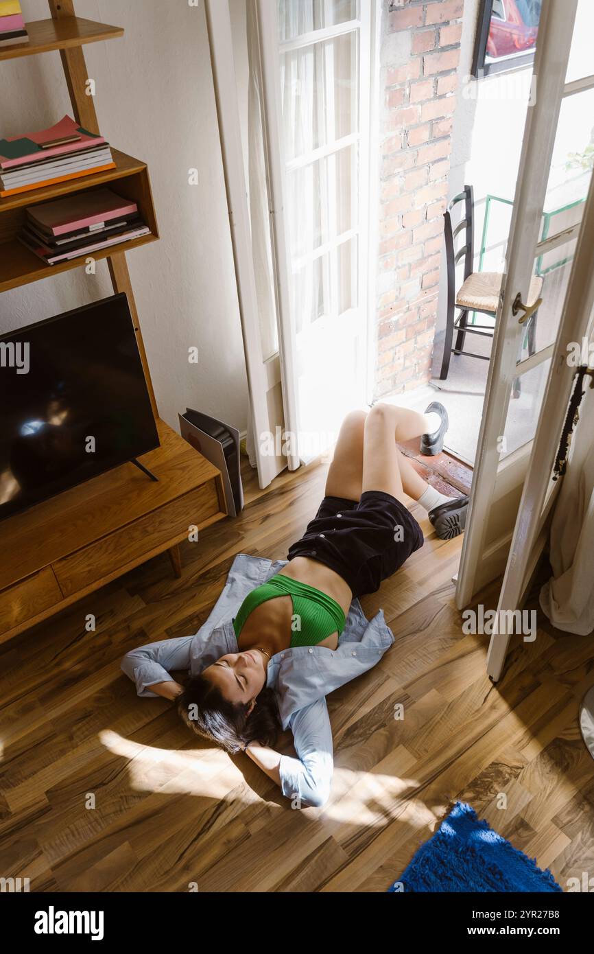 High angle view of woman lying down on hardwood floor at home Stock Photo