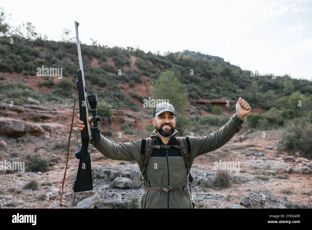 Happy hunter raising arms holding rifle in the air Stock Photo - Alamy