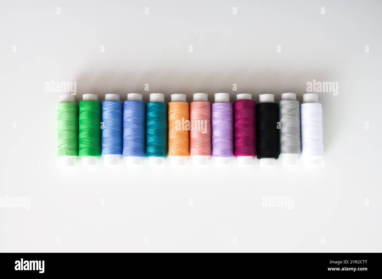 Many colorful sewing threads on light background. Stock Photo
