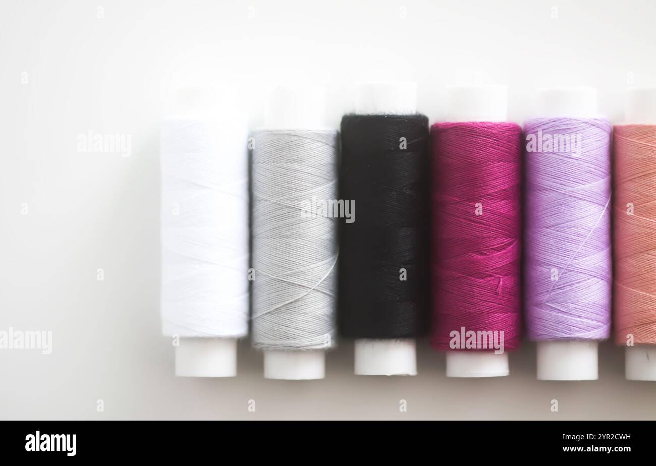 Many colorful sewing threads on light background. Stock Photo