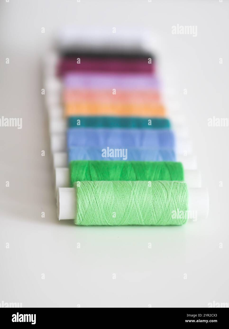 Many colorful sewing threads on light background. Stock Photo