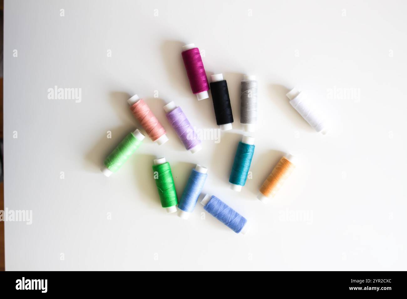 Many colorful sewing threads on light background. Stock Photo