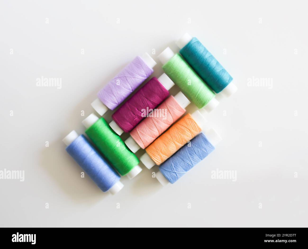 Many colorful sewing threads on light background. Stock Photo