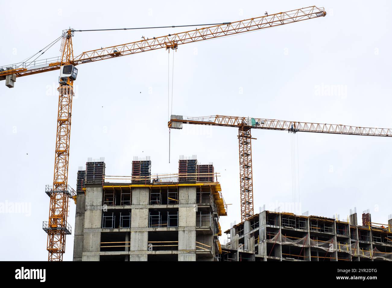A bustling construction site featuring cranes towering above, with a large building currently undergoing construction and development Stock Photo