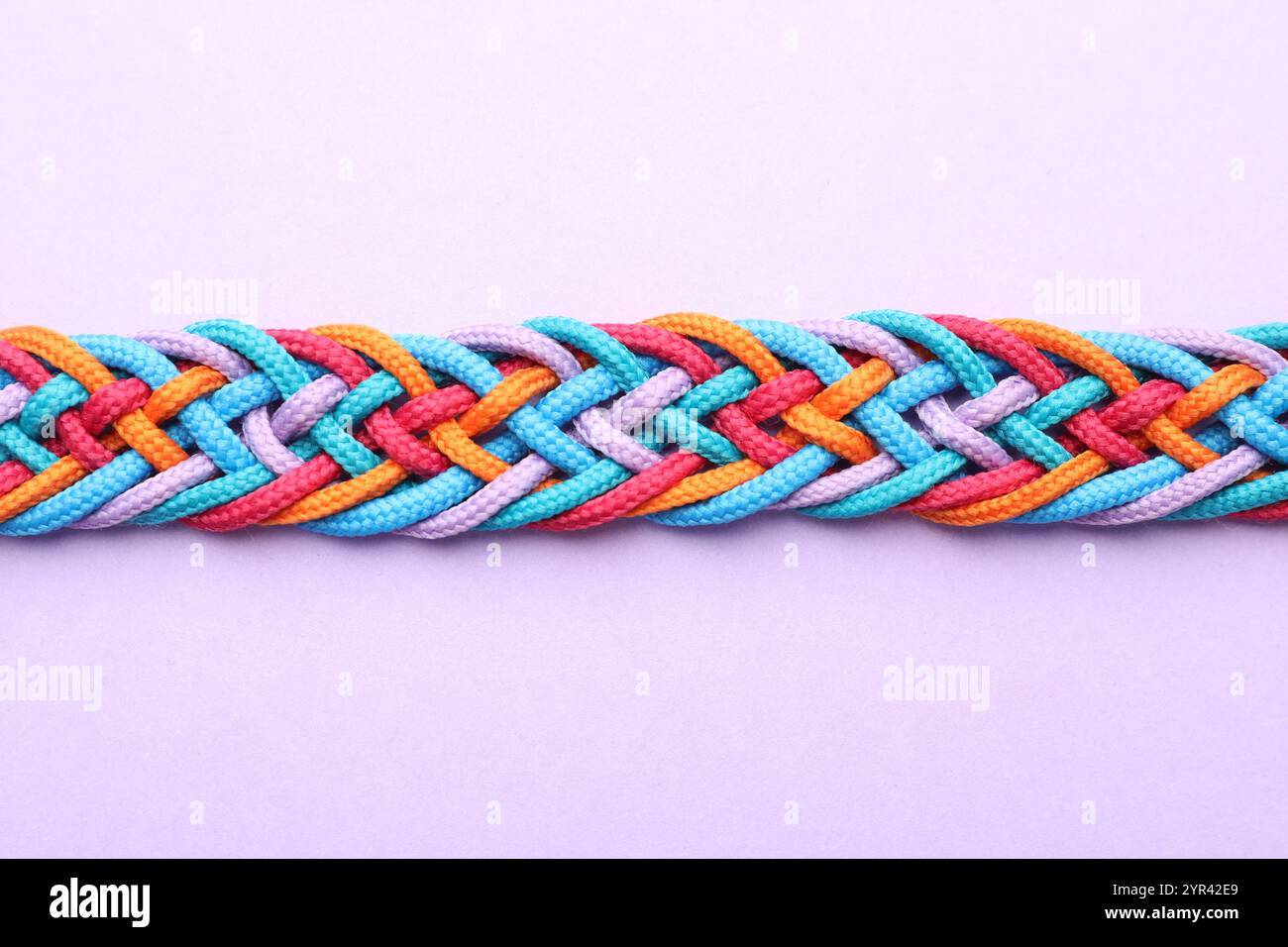 Braided colorful ropes on violet background, top view. Unity concept ...