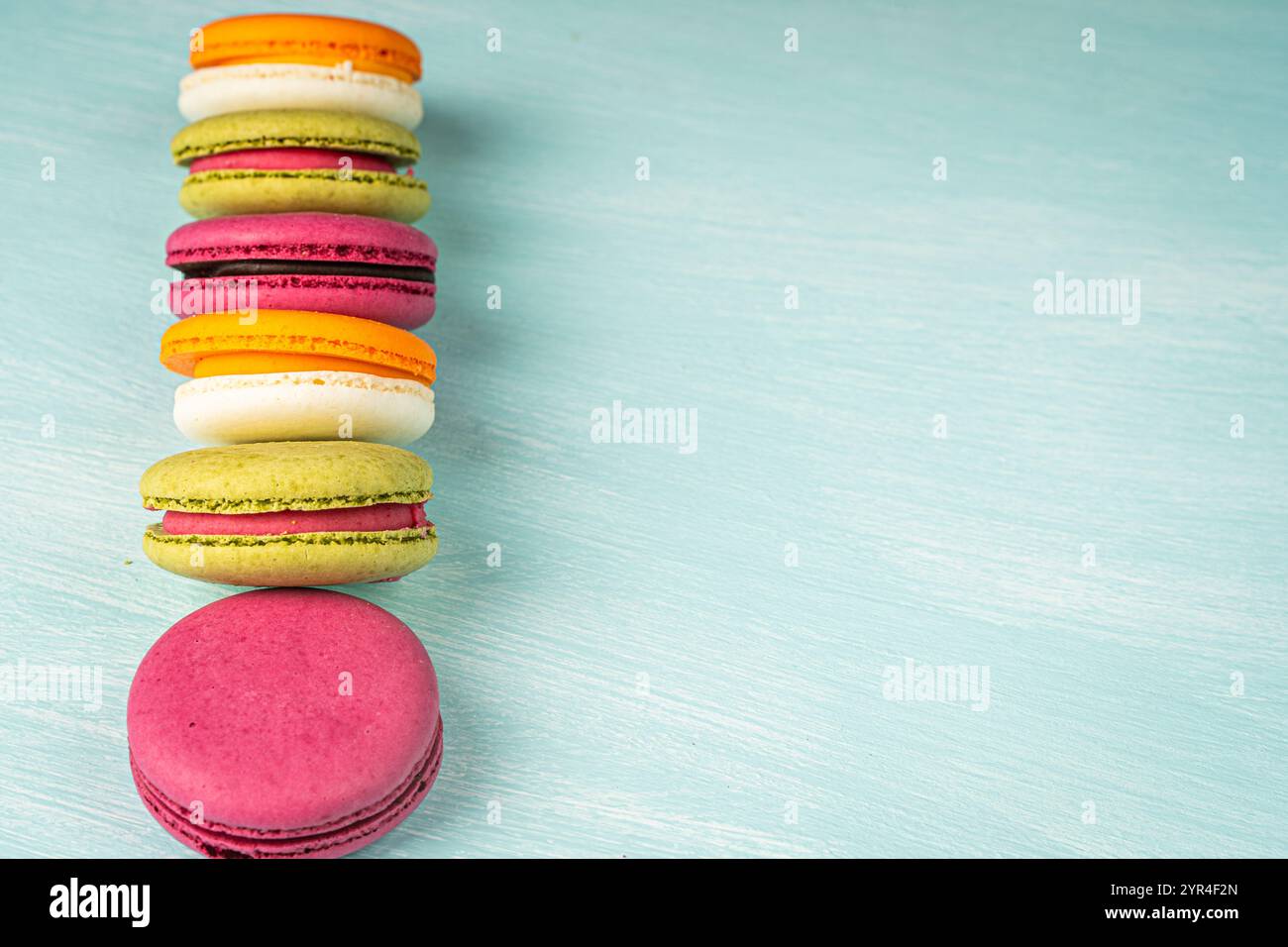 Multi-colored macaroons are stacked. Cherry, pistachio and mango macaroons on a light blue background. Copyspace, Place for text. High quality photo Stock Photo