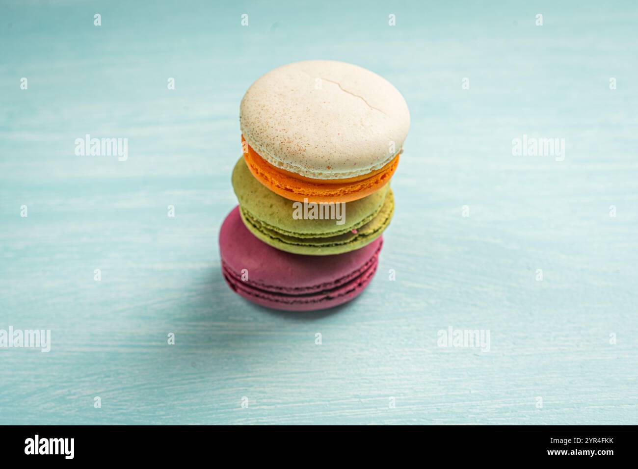Multi-colored macaroons are stacked. Cherry, pistachio and mango macaroons on a light blue background. Copyspace, Place for text. High quality photo Stock Photo