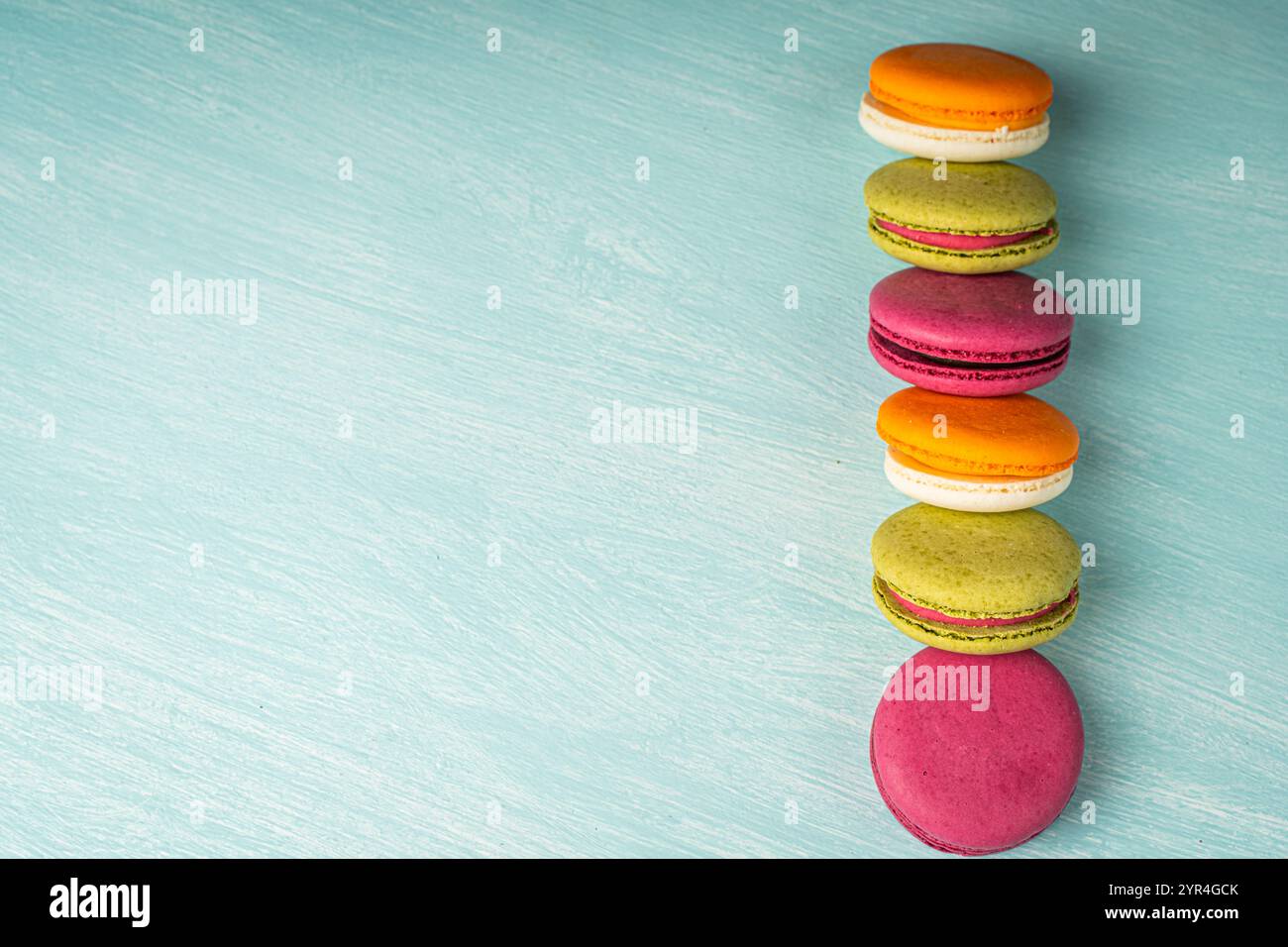 Multi-colored macaroons are stacked. Cherry, pistachio and mango macaroons on a light blue background. Copyspace, Place for text. High quality photo Stock Photo