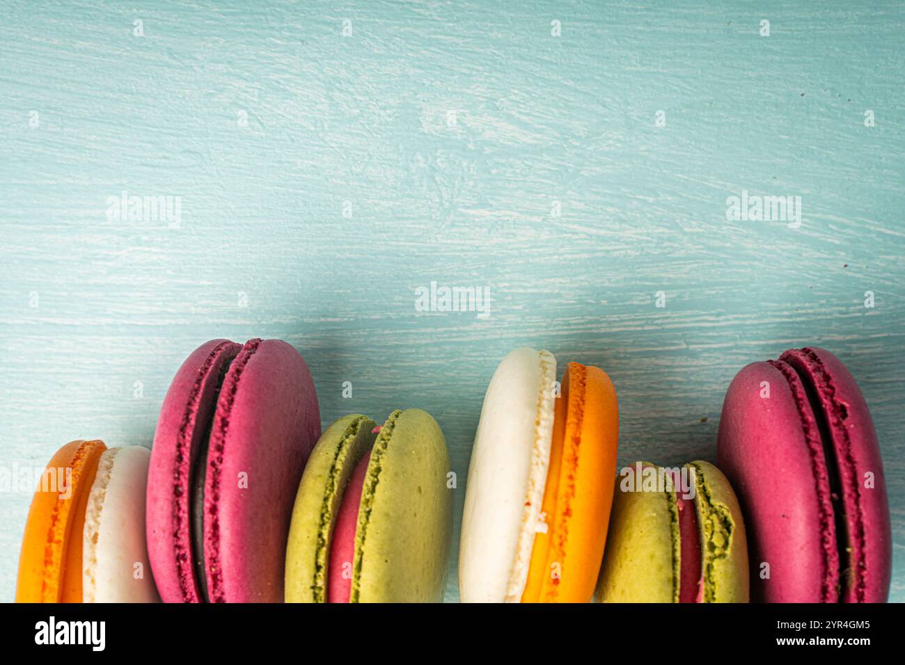 Multi-colored macaroons are stacked. Cherry, pistachio and mango macaroons on a light blue background. Copyspace, Place for text. High quality photo Stock Photo